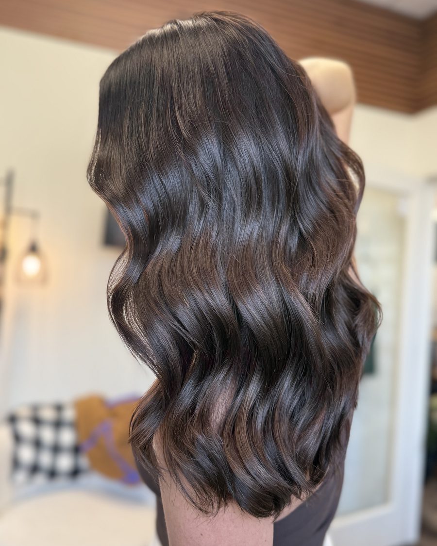 Glossy dark brunette waves with added density from Invisible Bead Extensions, photographed from behind with no visible rows